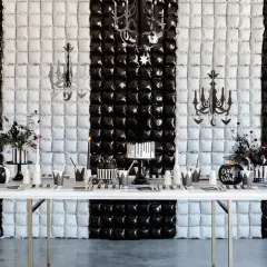 Table dressée pour une activité anniversaire mercredi Addams : gâteau, citrouille, décorations gothiques sur fond rayé noir et blanc.