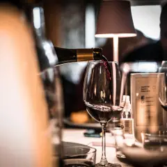 Verre de vin rouge servi dans un bar, ambiance feutrée.