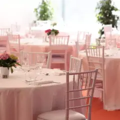 Tables dressées pour un mariage sans traiteur, avec des chaises blanches et des centres de table floraux.