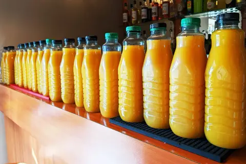 Une longue rangée de bouteilles de jus d'orange, prêtes pour une fête. 5 litres de punch pour combien de personnes ?