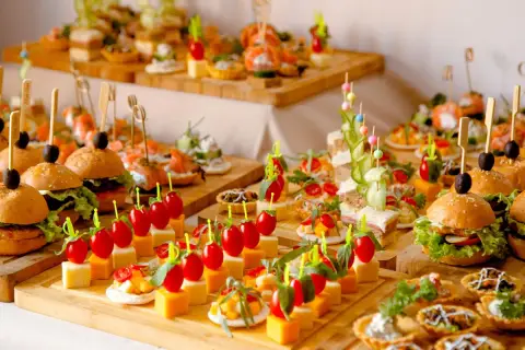 Un apéro dinatoire pour 10 personnes : mini-burgers, brochettes de tomates-mozzarella, tartines et verrines joliment dressés sur des planches en bois.
