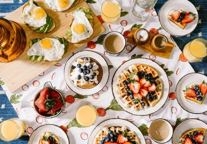Idée repas pour soirée association : brunch festif avec gaufres aux fruits, toasts avocat-œuf, et jus d'orange.
