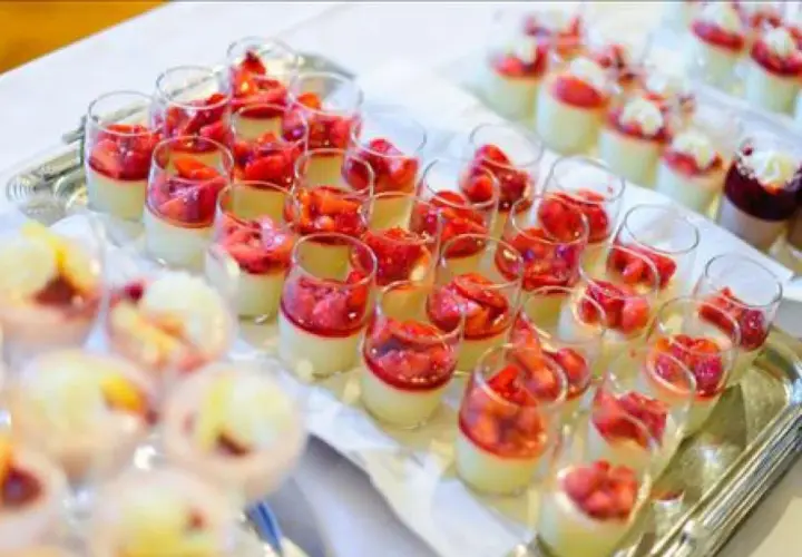 Plateau de mini dessert pour buffet : verrines crémeuses garnies de fraises fraîches et d'une touche de coulis rouge.