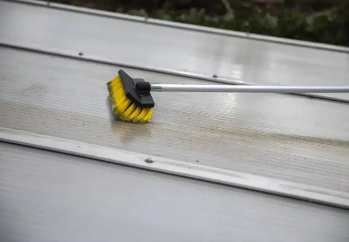 Brosse jaune et noire sur une surface striée en aluminium, en cours de nettoyage.