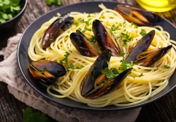 Un plat de spaghetti aux moules, parsemé de persil frais. Un accompagnement parfait pour des moules savoureuses.
