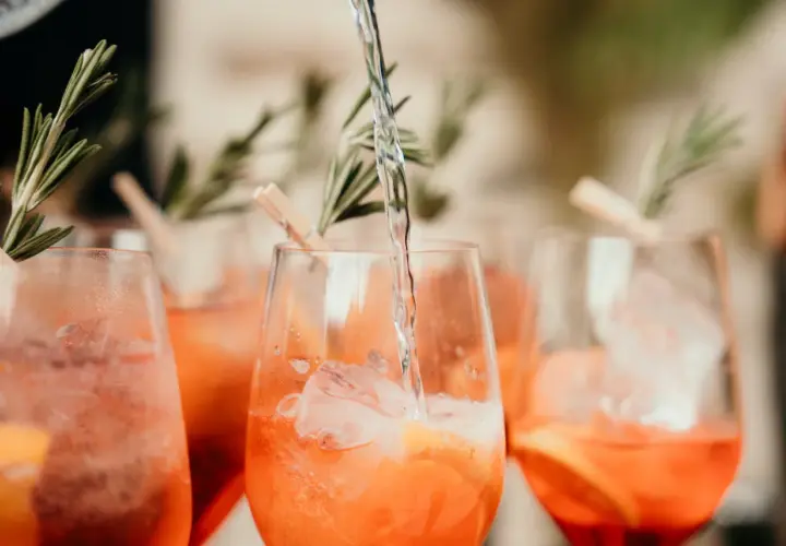 Verre de boisson soft mariage rempli de glaçons et d'une tranche d'orange, garni de romarin.