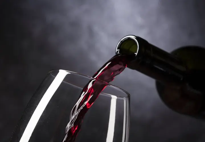 Vin rouge versé d'une bouteille dans un verre. Le moment idéal pour estimer un vin avant de le déguster.