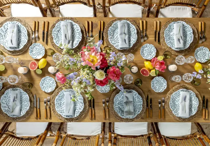 Table dressée pour un repas mariage champêtre, avec fleurs, fruits et vaisselle décorée de feuilles vertes.