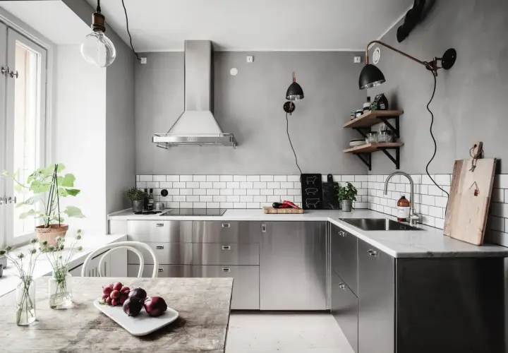 Cuisine moderne avec armoires en inox, parfait pour comment reconnaître de l'inox. Le plan de travail en marbre et le carrelage métro blanc complètent le look.