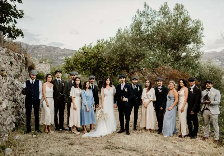Mariage Peaky Blinders : le couple et leurs témoins, tous habillés de costumes d'époque, posent devant un paysage rocheux et verdoyant.