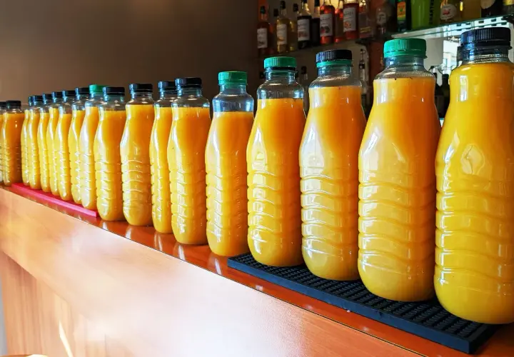 Une longue rangée de bouteilles de jus d'orange, prêtes pour une fête. 5 litres de punch pour combien de personnes ?