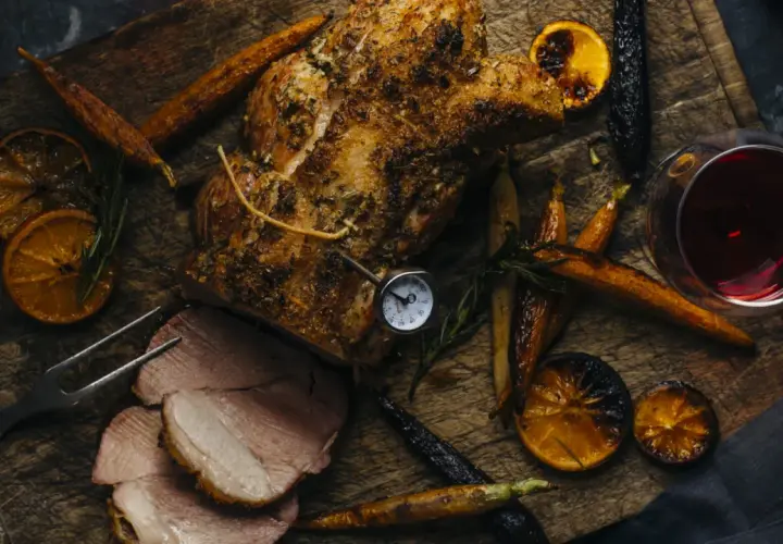 Un rôti de porc savoureux, accompagné de carottes rôties, d'oranges caramélisées et d'un verre de vin rouge. Parfait pour un repas d'automne.