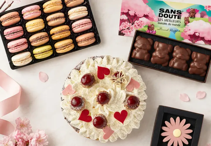 Un délicieux dessert pour la fête des grands-mères : une tarte garnie de fruits rouges et de crème, accompagnée de macarons colorés et de chocolats en forme d'oursons.