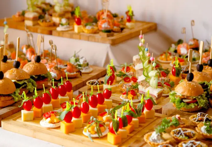 Un apéro dinatoire pour 10 personnes : mini-burgers, brochettes de tomates-mozzarella, tartines et verrines joliment dressés sur des planches en bois.