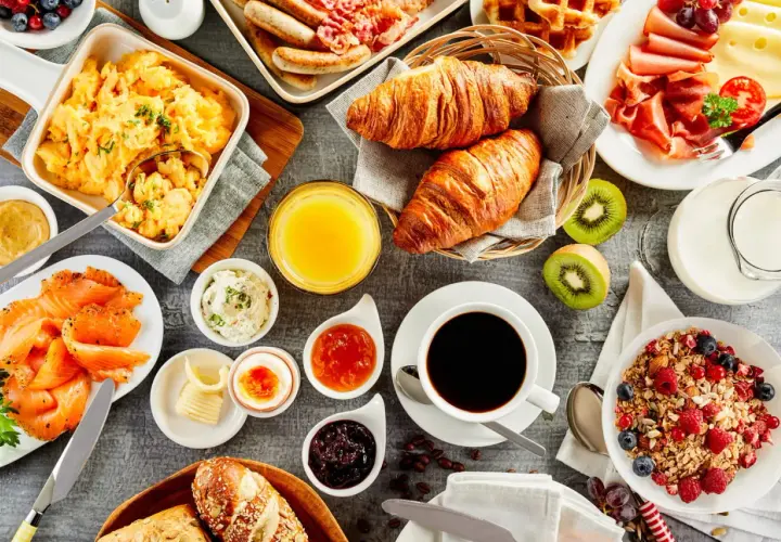 Un festin pour un brunch mariage : œufs brouillés, saumon fumé, croissants, fruits, café et granola.
