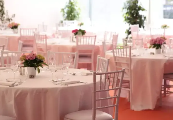 Tables dressées pour un mariage sans traiteur, avec des chaises blanches et des centres de table floraux.