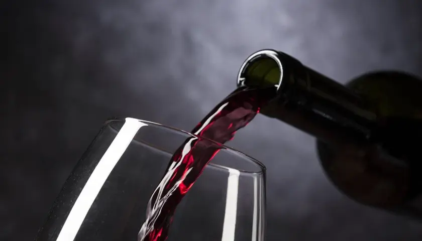 Vin rouge versé d'une bouteille dans un verre. Le moment idéal pour estimer un vin avant de le déguster.