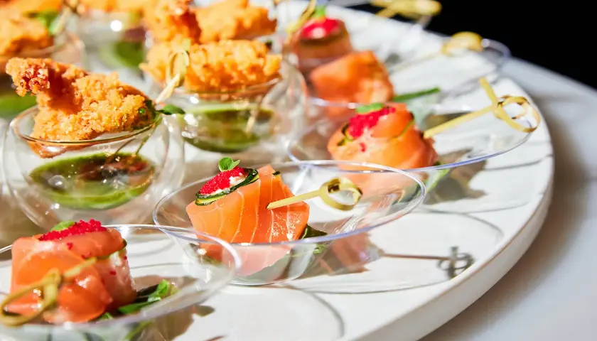 Un plateau d'apéro dinatoire américain avec des crevettes croustillantes et des roulés de saumon aux œufs de poisson.