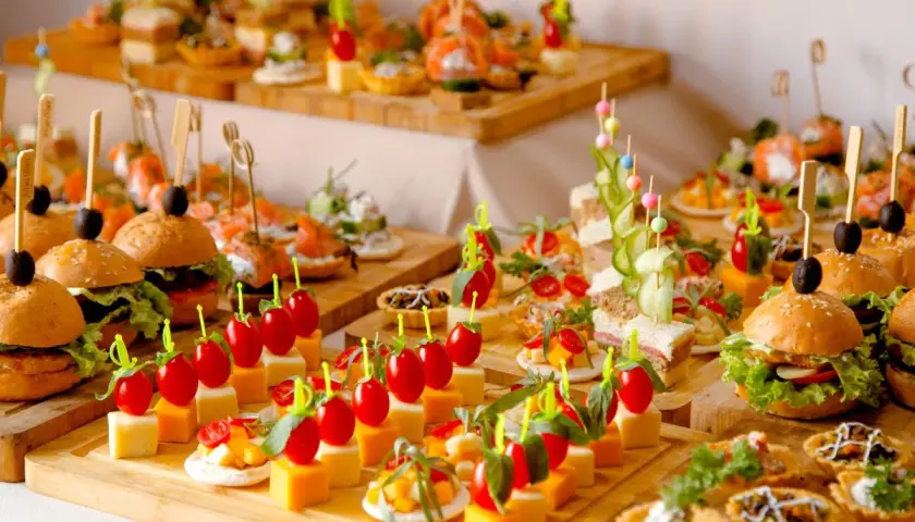Un apéro dinatoire pour 10 personnes : mini-burgers, brochettes de tomates-mozzarella, tartines et verrines joliment dressés sur des planches en bois.