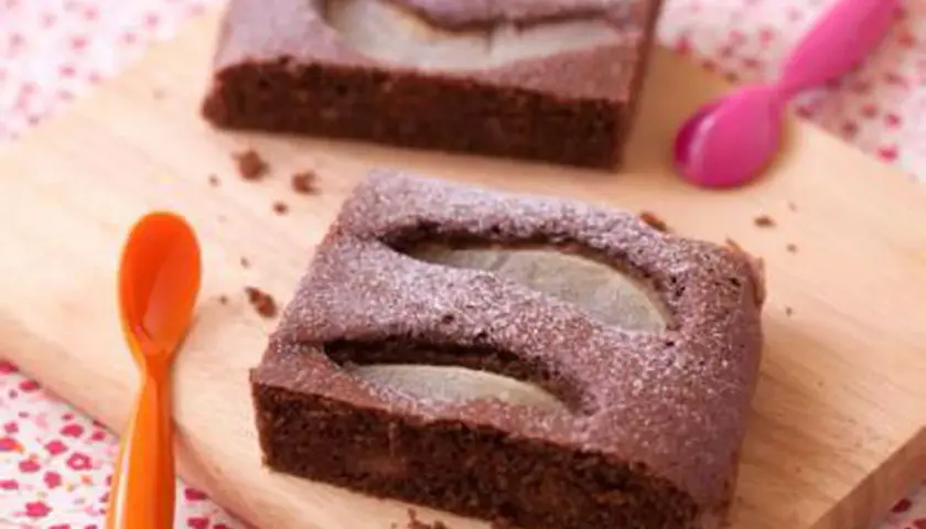Gâteau au chocolat et poire, saupoudré de sucre glace. Une idée pour apporter un dessert original et gourmand.