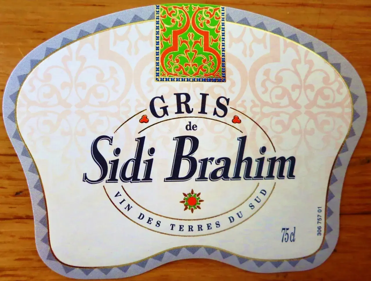 Étiquette de vin Sidi Brahim Gris, avec un motif floral vert et rouge en haut. Le texte "Sidi Brahim" est en gros caractères bleus.