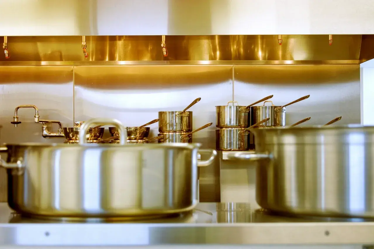 Une cuisine professionnelle avec des casseroles en inox 18/0 étincelantes sous une hotte aspirante.