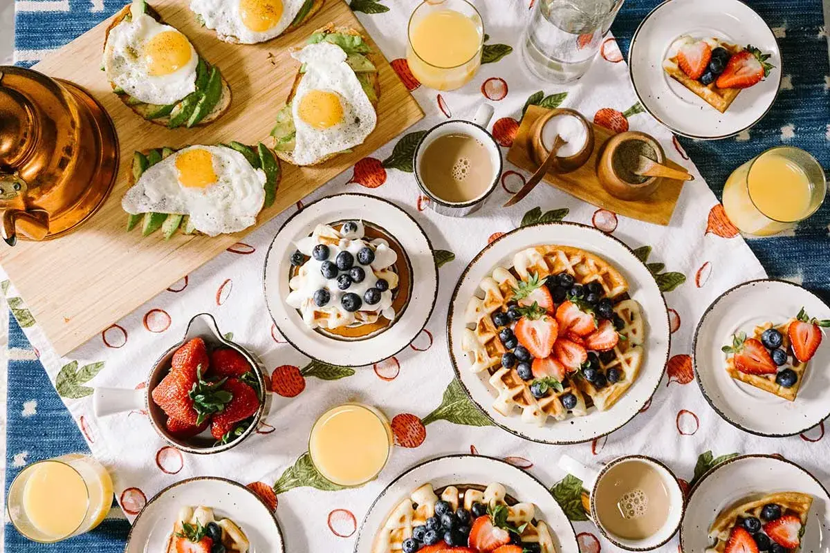 Idée repas pour soirée association : brunch festif avec gaufres aux fruits, toasts avocat-œuf, et jus d'orange.