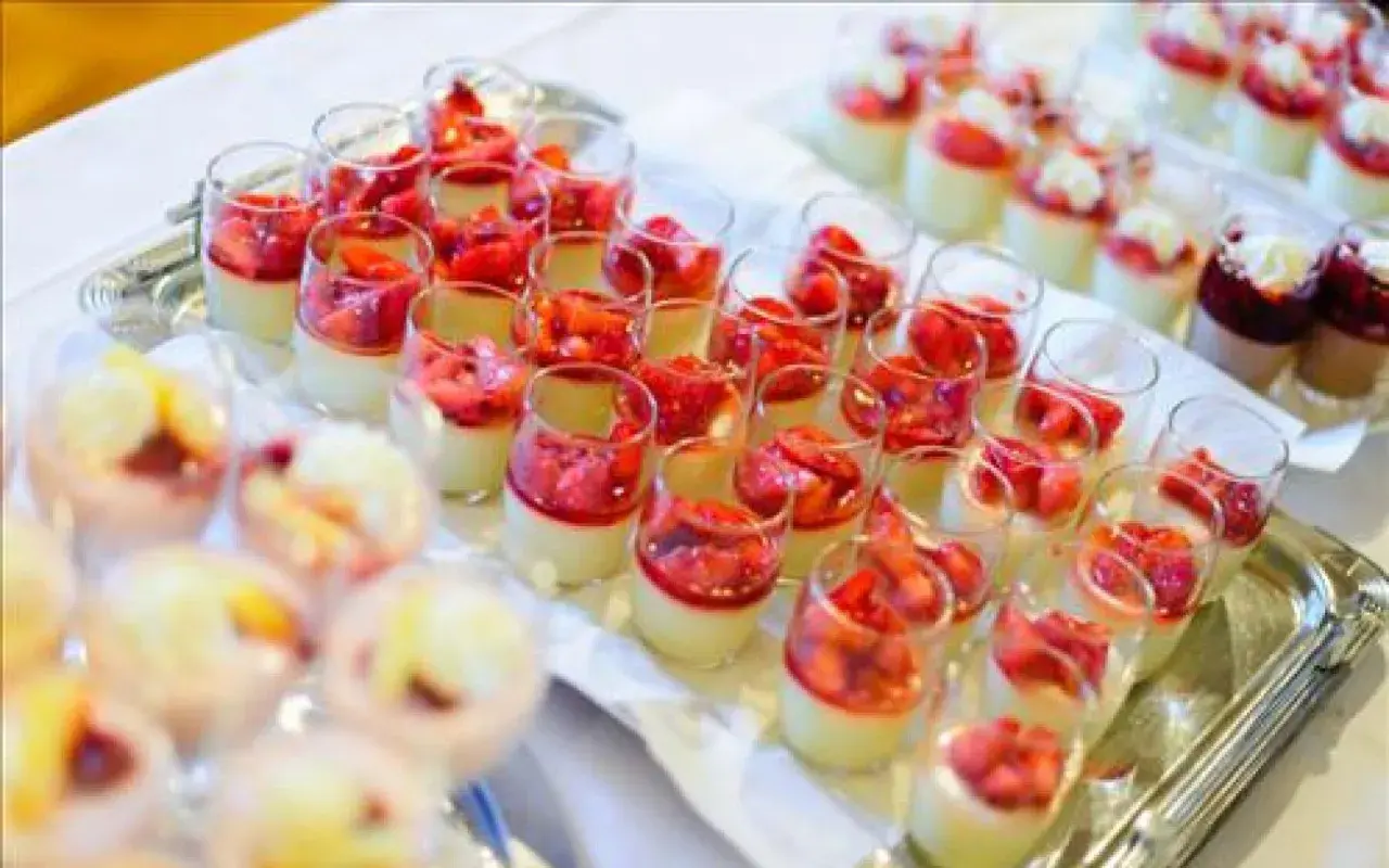 Plateau de mini dessert pour buffet : verrines crémeuses garnies de fraises fraîches et d'une touche de coulis rouge.