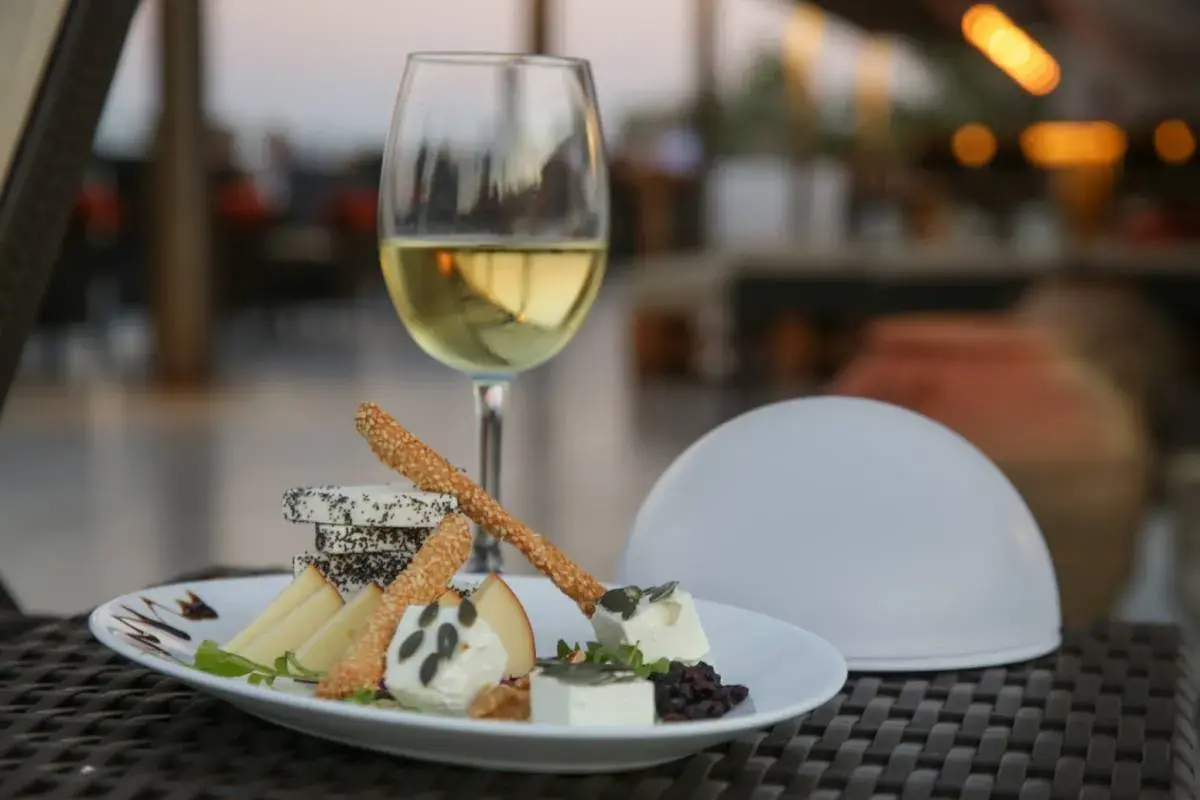 Un verre de vin blanc et une assiette de fromages variés, parfaits pour savoir que manger avec un gewurztraminer.
