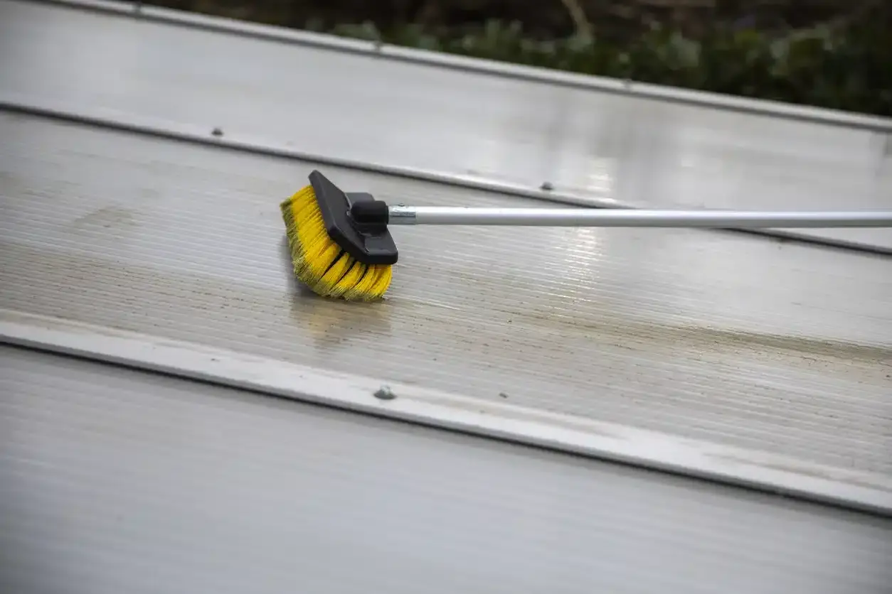 Brosse jaune et noire sur une surface striée en aluminium, en cours de nettoyage.