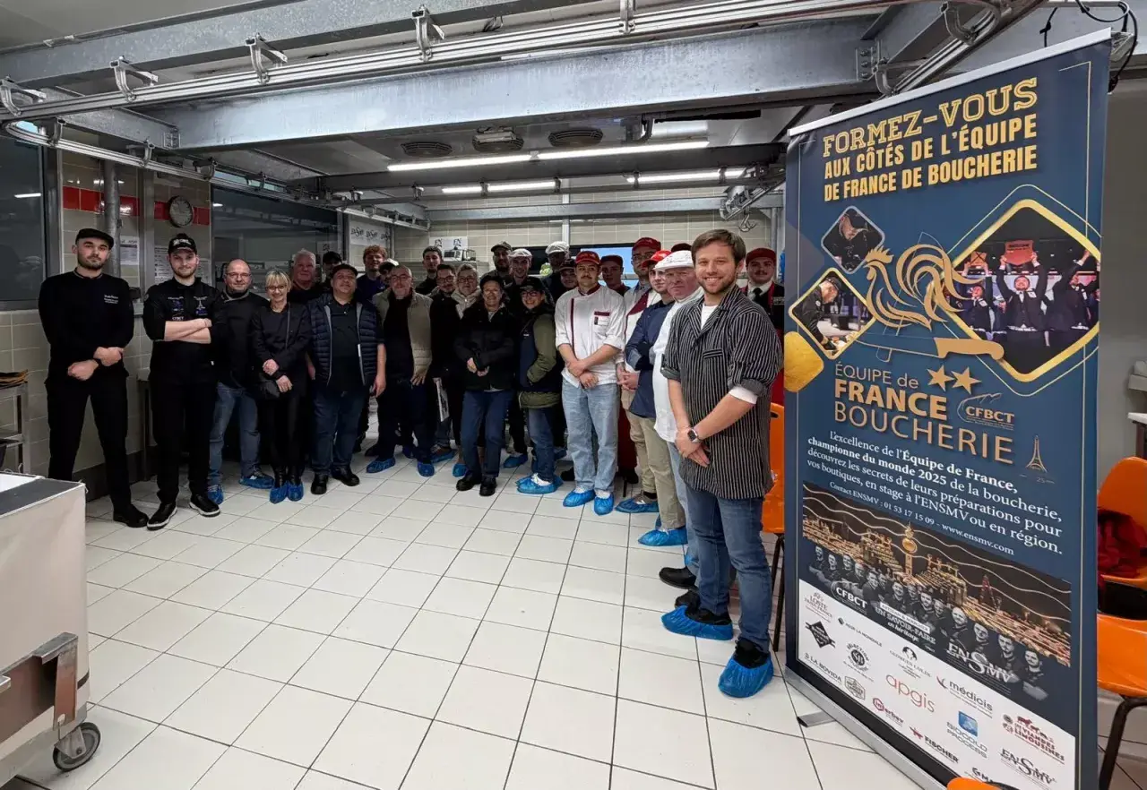 Une équipe de bouchers pose devant une bannière "Équipe de France Boucherie". Une idée de préparation boucherie pour le championnat du monde.
