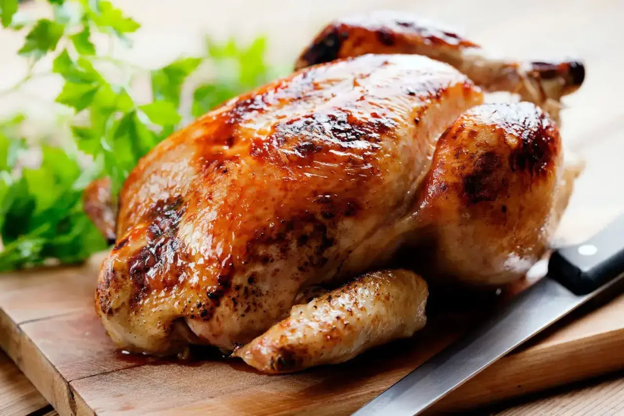 Un délicieux poulet rôti doré sur une planche en bois, prêt à être dégusté. Quel vin avec poulet rôti ? Un blanc fruité ou un rouge léger serait parfait.