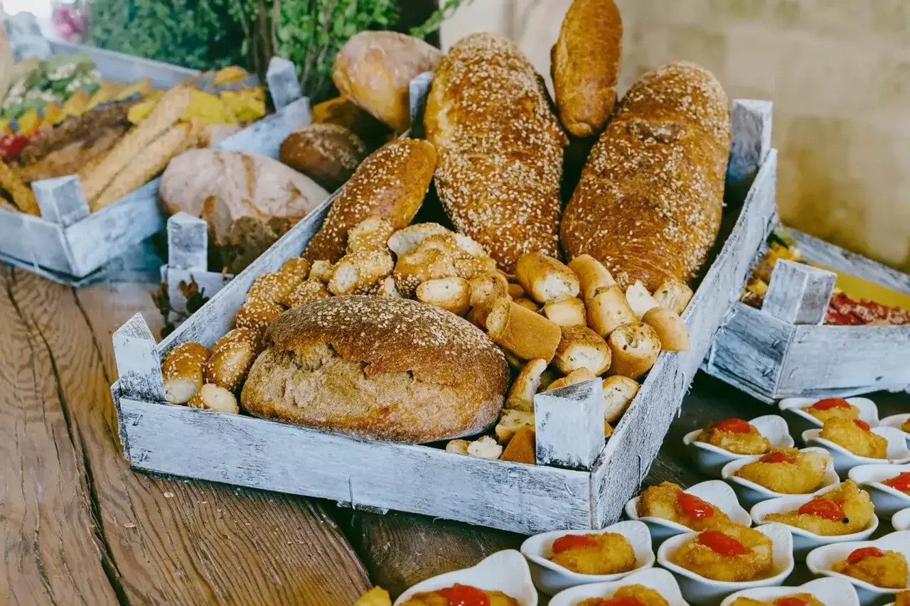 Plateau de pains variés, idéal pour organiser un petit déjeuner pour 30 personnes. Des miches rondes, des baguettes aux graines de sésame et des petits pains croustillants.