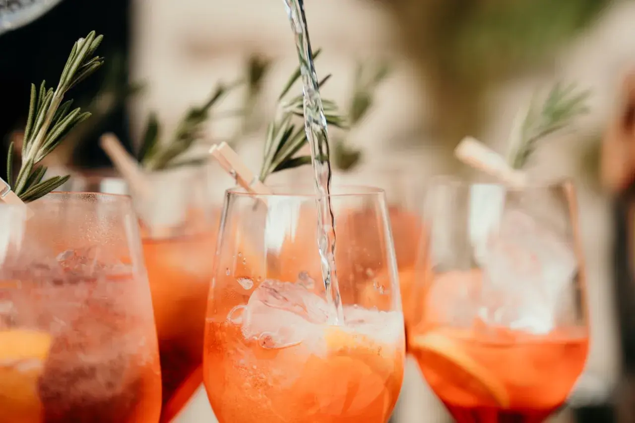 Verre de boisson soft mariage rempli de glaçons et d'une tranche d'orange, garni de romarin.