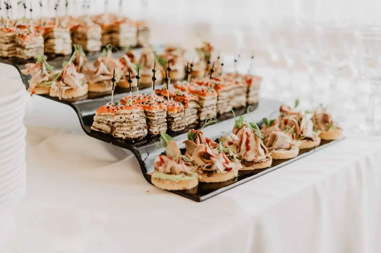 Petits fours variés sur un plateau noir, parfaits pour un mariage avec un budget alcool maîtrisé.