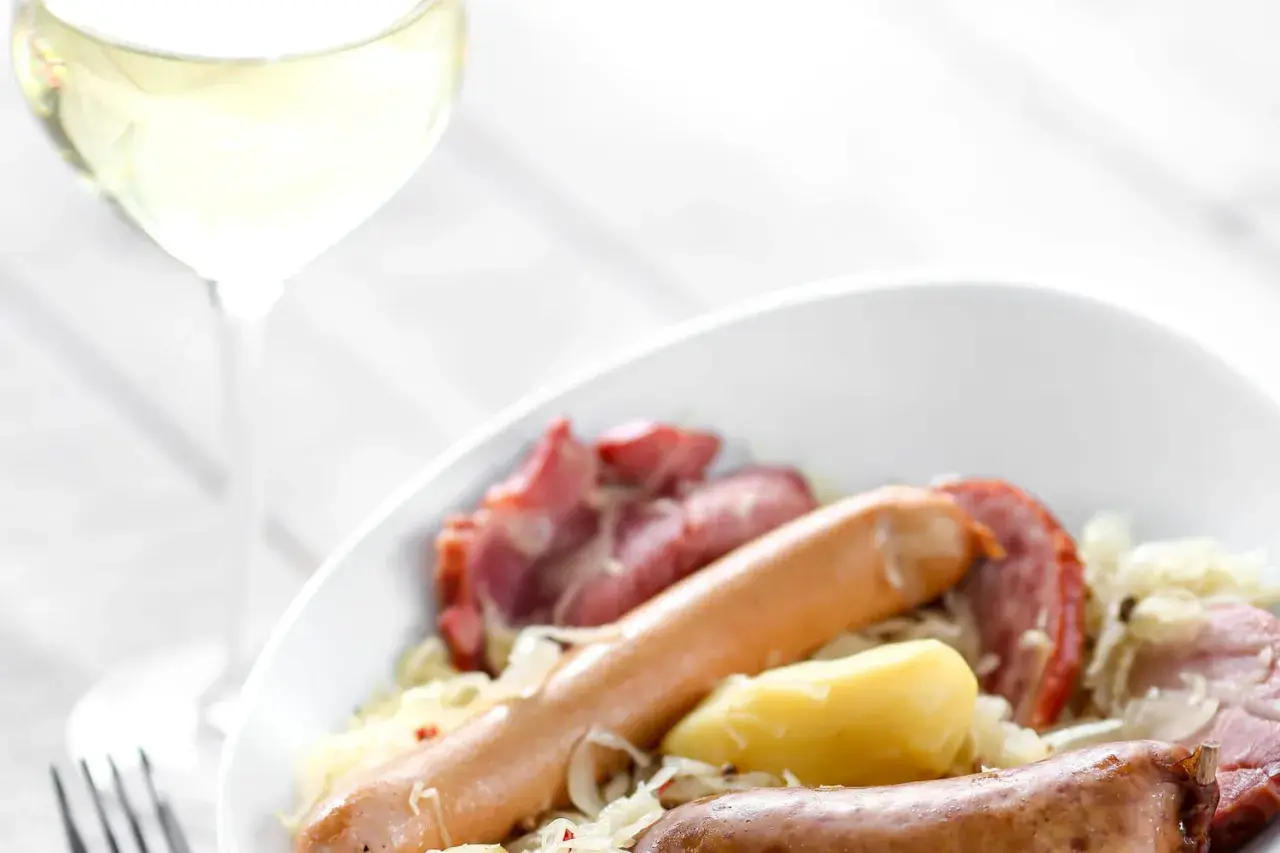 Un verre de vin blanc accompagne une choucroute de la mer généreuse avec saucisses et pommes de terre. Quel vin avec choucroute de la mer ?