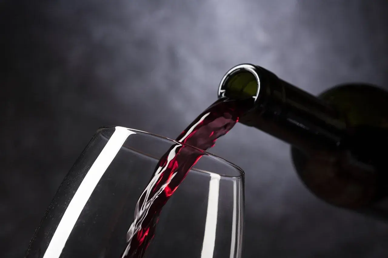 Vin rouge versé d'une bouteille dans un verre. Le moment idéal pour estimer un vin avant de le déguster.