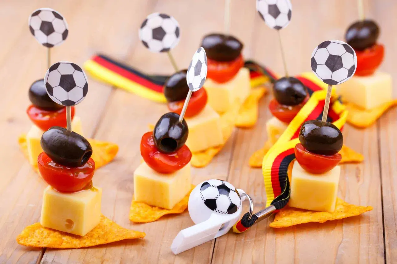Ambiance parfaite pour une soiree foot : petits fours avec des ballons, des olives, des tomates et des drapeaux allemands.