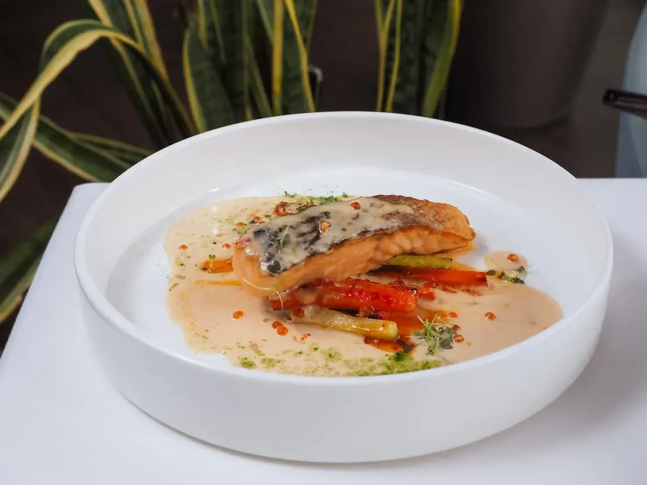 Un filet de poisson poêlé, baignant dans une onctueuse sauce champagne, accompagné de légumes croquants et de quelques perles orangées.