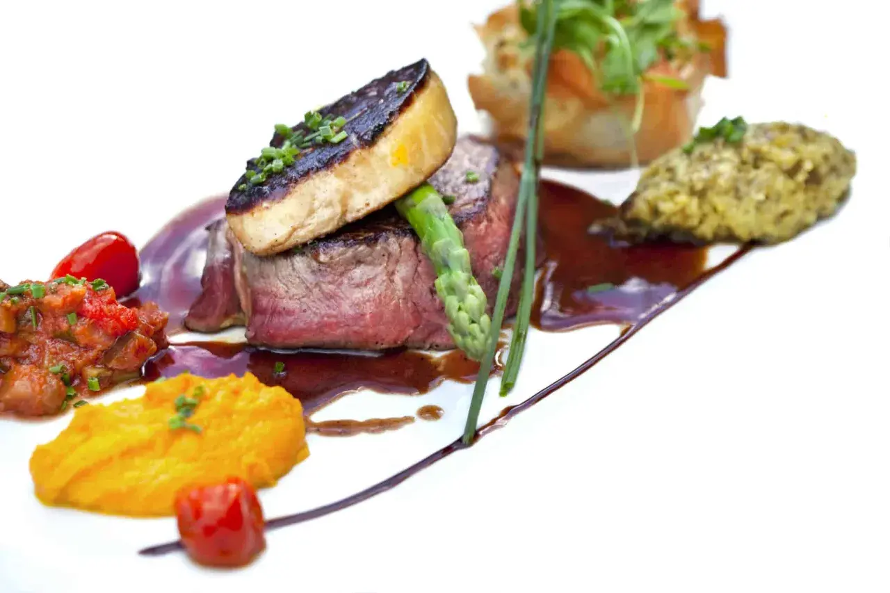 Un steak tendre surmonté de foie gras poêlé, accompagné de purée de patates douces et d'une ratatouille. Un plat qui invite à se demander quoi boire avec du foie gras.