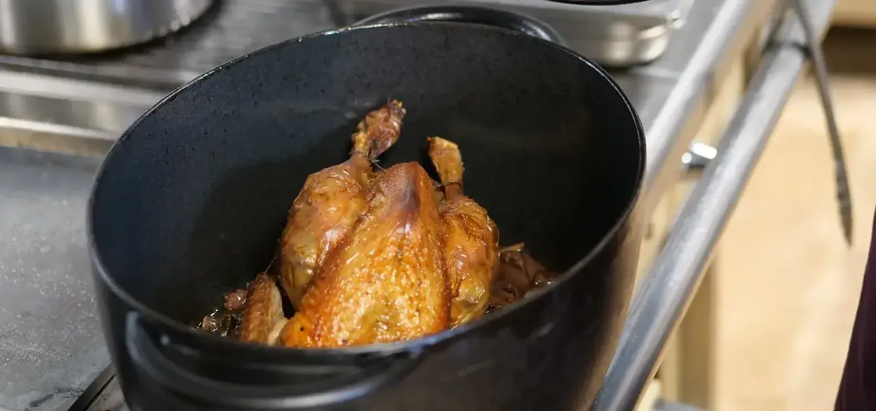 Un poulet rôti doré dans une cocotte. Quel vin rouge avec du poulet ? Un Pinot Noir léger ou un Beaujolais fruité serait parfait.