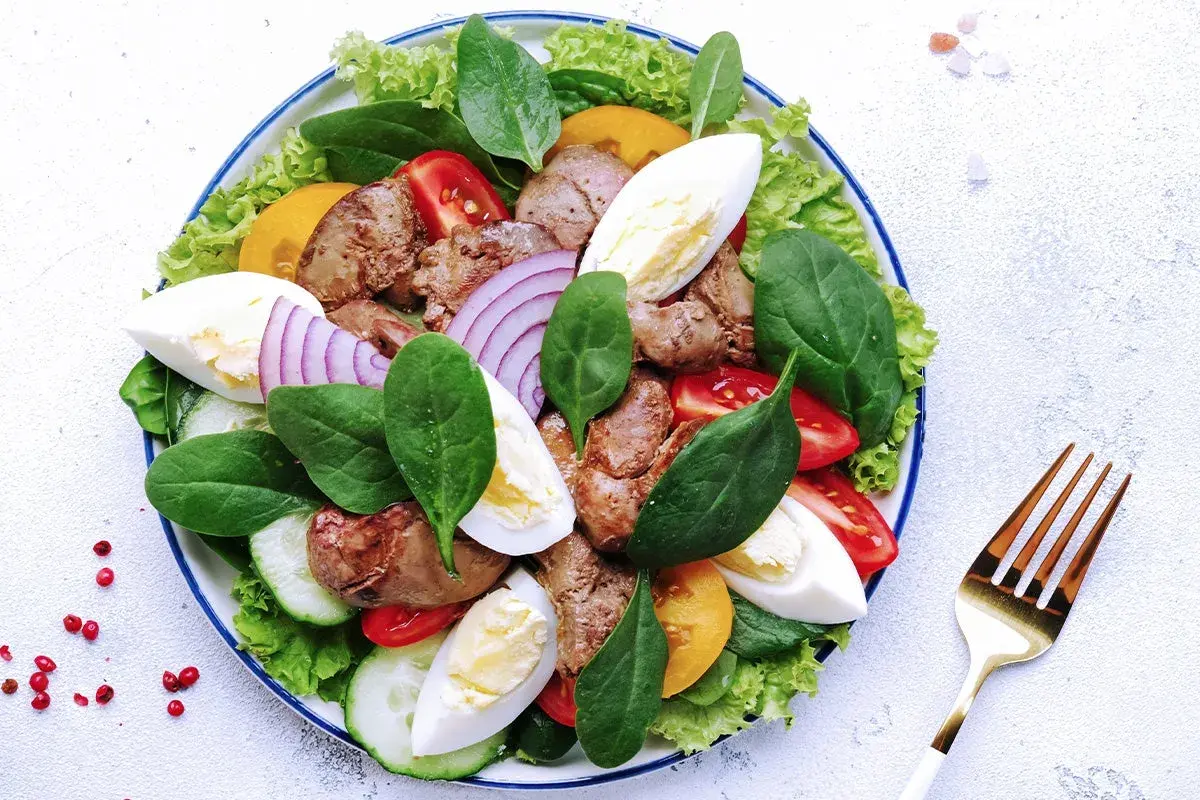 Salade Landaise appétissante avec foies de volaille, œufs durs, tomates, oignons rouges et légumes verts. Quel vin avec une salade landaise ? Un vin blanc sec et fruité.