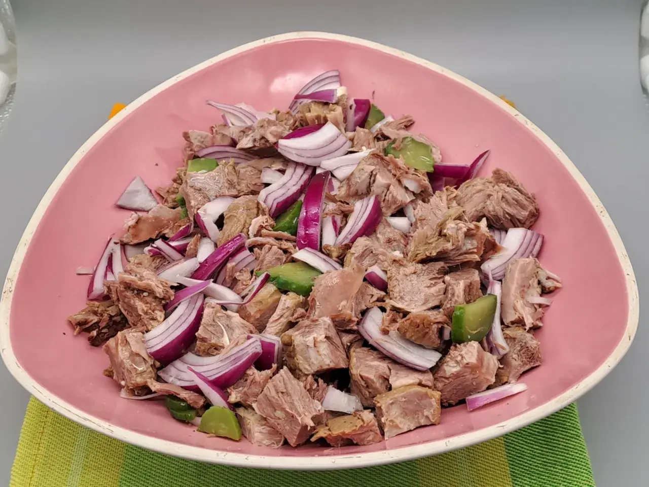 Salade de viandes froides, un plat savoureux avec des morceaux de viande, des oignons rouges et des avocats, servi dans un bol rose.