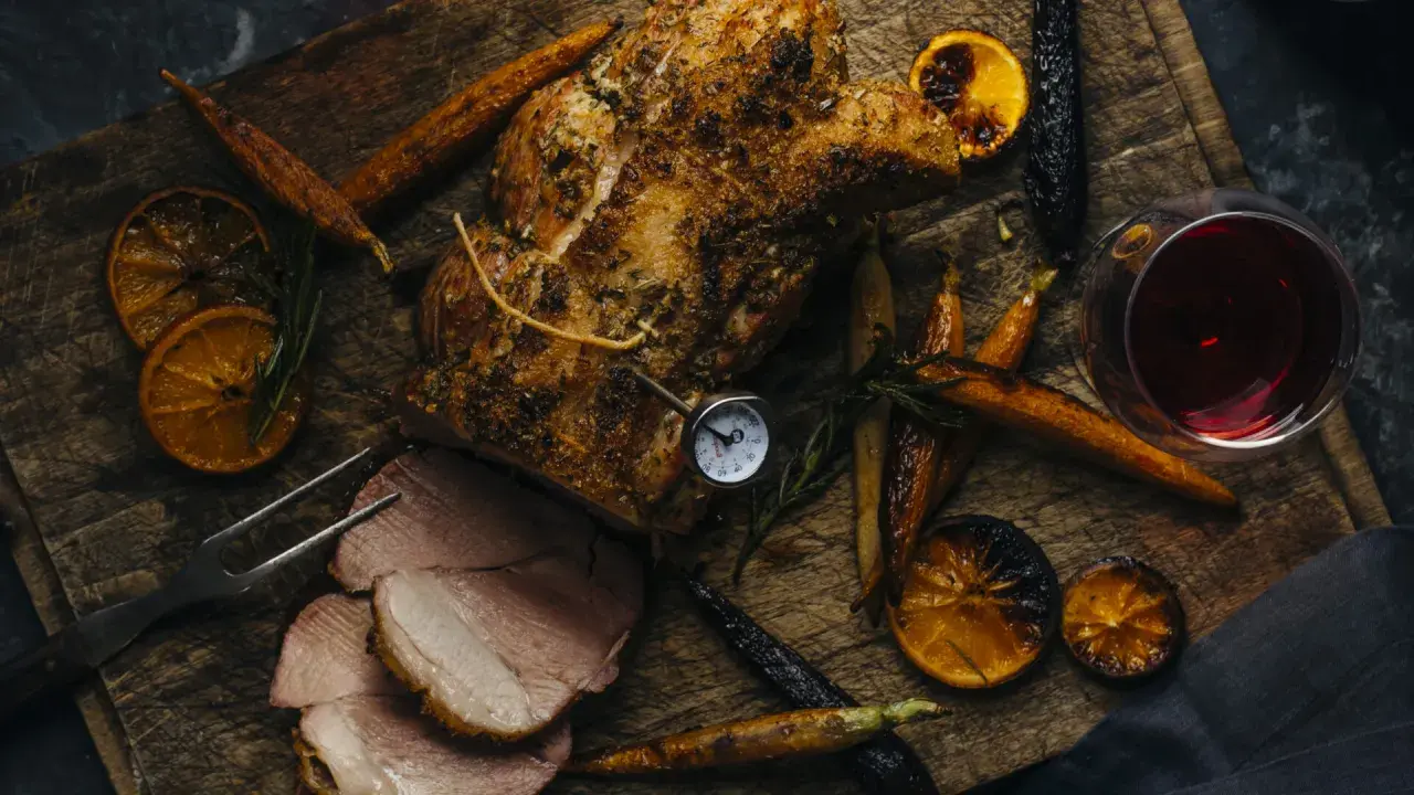 Un rôti de porc savoureux, accompagné de carottes rôties, d'oranges caramélisées et d'un verre de vin rouge. Parfait pour un repas d'automne.