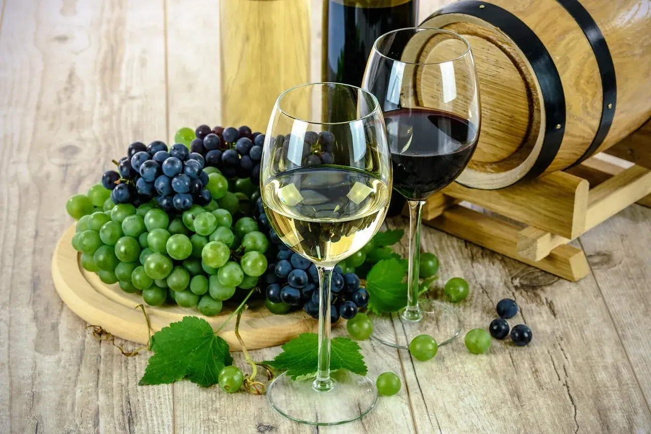 Deux verres de vin, rouge et blanc, accompagnés de grappes de raisins et d'un fût de chêne. Un millésime haut Médoc promet une dégustation exquise.