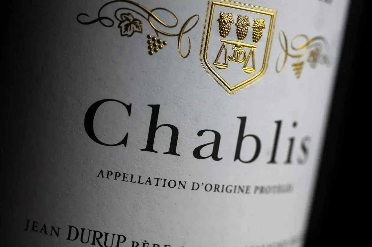 Gros plan sur l'étiquette d'une bouteille de Chablis, avec un blason doré. La conservation de ce vin est essentielle pour apprécier sa finesse.