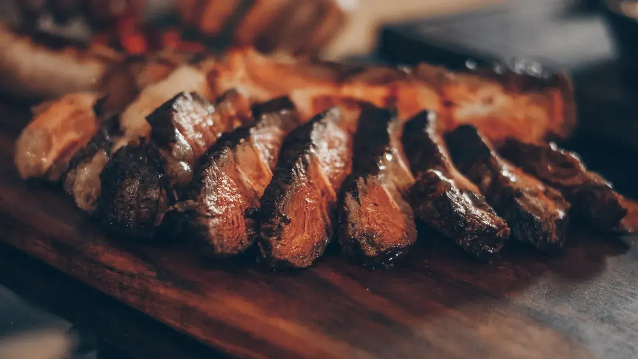 Tranches de viande grillée sur une planche en bois. Idéal pour savoir quel vin avec une pierrade.