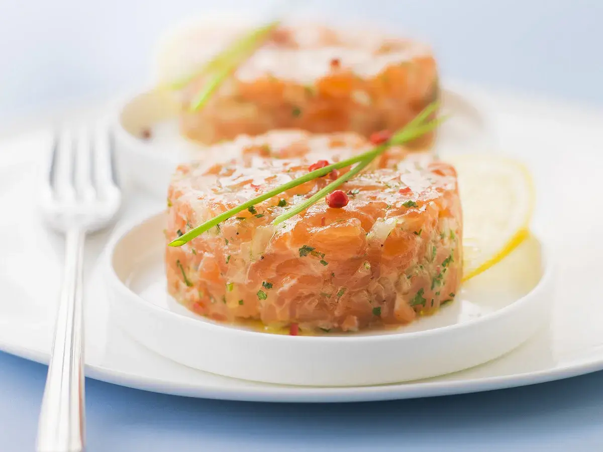 Deux tartares de saumon frais, garnis de ciboulette et de poivre rose, prêts à être dégustés. Parfait pour savoir que boire avec un tartare de saumon.