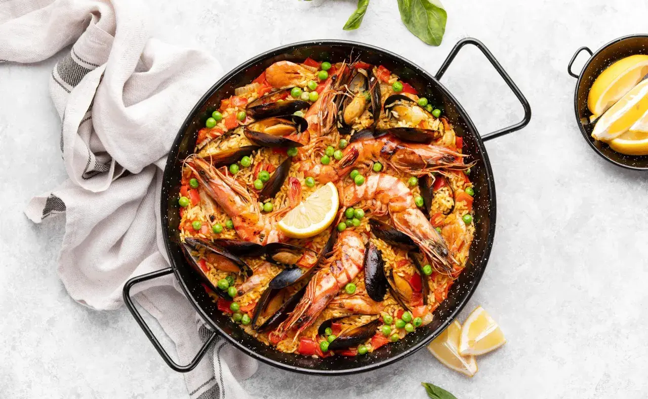 Paella royale aux crevettes et moules, garnie de pois et de citron. Quel vin avec la paella royale ? Un vin blanc sec et fruité, ou un rosé léger.