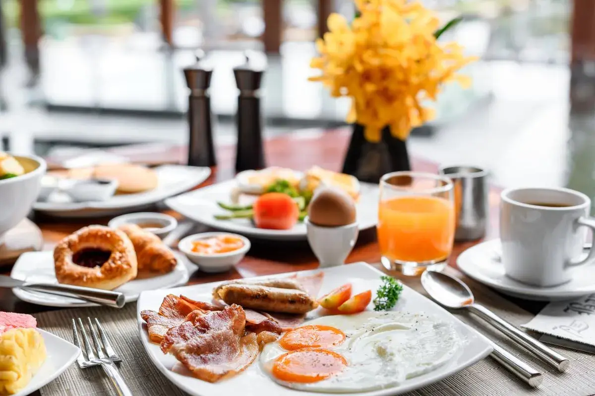 Un copieux petit déjeuner continental ou américain avec œufs, bacon, saucisses, viennoiseries, jus d'orange et café.